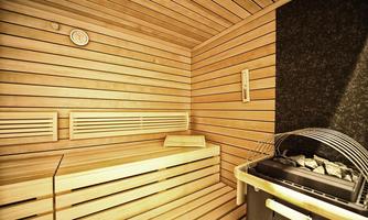 A sauna with wooden paneling and user-friendly benches. In the background, a stove and a thermometer are visible.