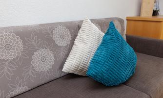 A modern sofa with a floral pattern and two cushions. One is light and the other is in vibrant turquoise.