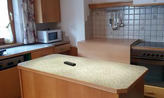A modern kitchen with wooden cabinets and a kitchen island. It is well-lit and has various kitchen appliances.