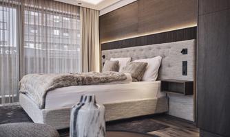 A modern bedroom with a comfortable bed and soft color tones. Large windows let in plenty of daylight and create an inviting atmosphere.