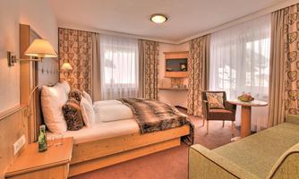 A cozy hotel room with a single bed and a seating area. Large windows provide plenty of natural light.