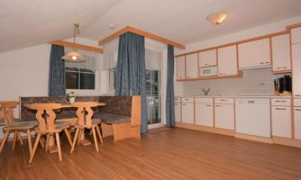 A bright and spacious kitchen with a dining table and chairs. The modern amenities and wooden floor create an inviting atmosphere.