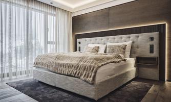 A modern bedroom with a cozy bed and soft bed linens. Large windows with curtains let in plenty of daylight.