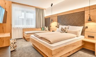 A modern bedroom with wooden furniture and a cozy atmosphere. The room is well-lit and offers a view outside.