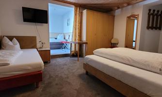 A cozy hotel room with two beds and a wooden ceiling. There is a television and a table in the room.
