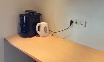 A small kitchen nook with a wooden tray. On the table are a coffee maker and a kettle.