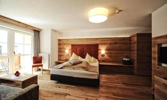 A modern room with wooden flooring and a cozy double bed.  
Large windows provide plenty of daylight and an inviting look.