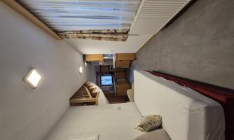 A cozy room with a single bed and a small kitchen. Large windows let in plenty of light, and the decor is friendly and modern.