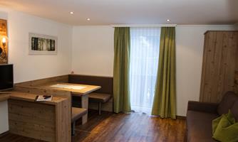 A bright living room with wood decor and a cozy dining area. Curtains in green create an inviting atmosphere.