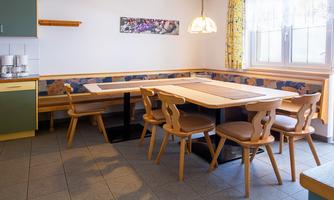 A cozy dining area with a large table and chairs. The windows let in plenty of light, and the walls are brightly designed.