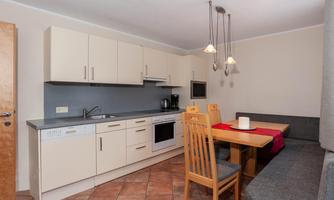 A modern kitchen with beige cabinets and a dining table. The decor is simple and functional, ideal for versatile use.