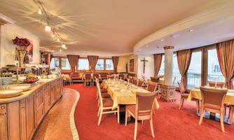 A cozy restaurant with wooden furniture and large windows. The space is warm and inviting, ideal for social meals.