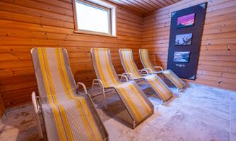 A small, cozy room with four recliners and wooden paneling. Pictures hang on the wall, emphasizing the relaxing atmosphere.