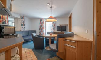 A cozy apartment with a dining area and a modern kitchen. The walls are bright, and the room is well lit.