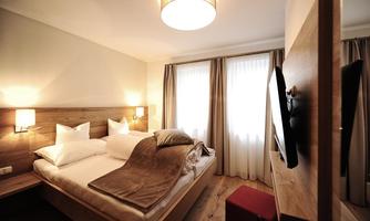 A cozy bedroom with a double bed and modern furniture. Bright curtains and soft light create a relaxed atmosphere.