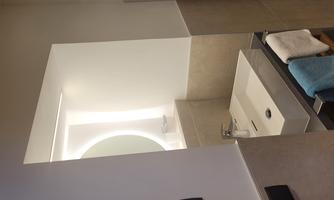 A modern bathroom with a sink and a large round mirror. Towels in various colors are neatly hung.