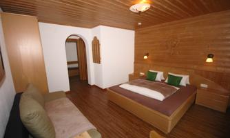 A cozy bedroom with wooden walls and a large double bed. The room is bright and inviting, perfect for relaxing.