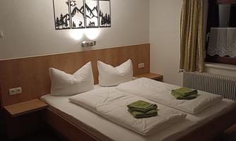 A cozy bright bedroom with a double bed and fresh towels. Shower cubicle and sink in the room.