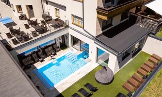 A modern courtyard with a swimming pool and sun loungers. Around the pool are comfortable seating options in an inviting atmosphere.