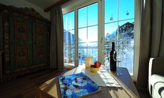 A cozy room with a view of the snowy landscape. On the table are apples and a bottle of wine.