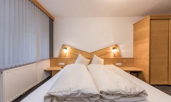 A modern bedroom with a double bed and two spacious pillows. The walls are light and the furniture is made of wood, which creates a cozy atmosphere.
