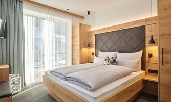 A modern bedroom with a large bed and wooden furniture.  
Plenty of natural light streams through the windows, creating a bright atmosphere.