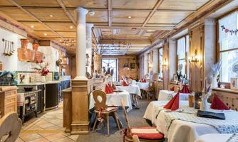 A cozy restaurant with wood decor and tablecloths. The tables are nicely set with red napkins.
