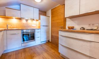 A modern kitchen with bright cabinets and wooden surfaces. It includes an oven and a spacious work area.