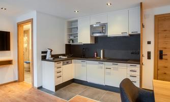 A modern kitchen with white cabinets and a dark countertop. The space has an open layout and plenty of light.