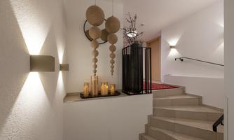 A tastefully decorated entrance area with stairs, soft lighting, and a candlestick arrangement. A modern art installation hangs on the wall.