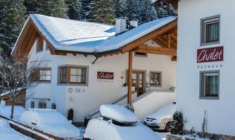 A charming chalet in the snow with a traditional wooden design. Surrounded by snow-covered trees, it conveys a cozy atmosphere.