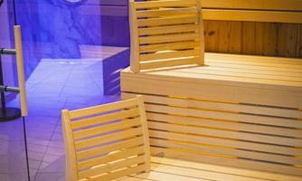 A modern sauna with bright wooden benches and relaxing lighting. The area looks clean and inviting.