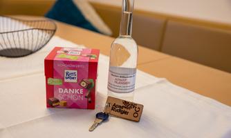 A gift set with chocolate from Ritter Sport and a bottle of water on a table. Next to it lies a keychain with the inscription "Apart Rüdiger".