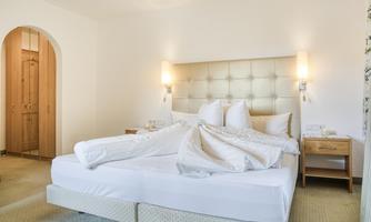 A cozy bedroom with a large bed and soft pillows. The room is bright and decorated in a modern style.