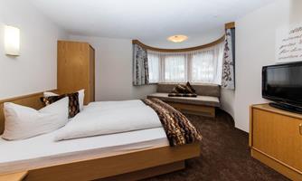 A cozy hotel room with a double bed and a seating area. Large windows let in plenty of light and create an inviting atmosphere.