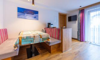 A modern room with a cozy dining area and bright decor. Large windows provide plenty of daylight and give access to a balcony.