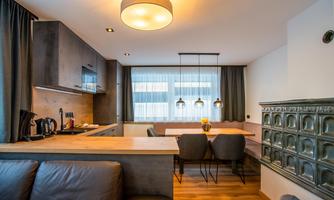 A modern kitchen with a dining area and elegant chairs. Large windows provide plenty of natural light.