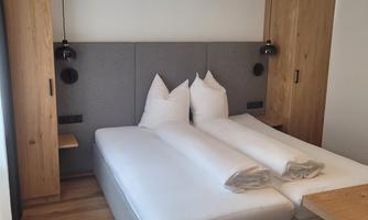 A modern bedroom with a double bed and light wooden furniture. There is a cozy atmosphere with minimalist decor.