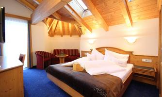 A cozy hotel room with wooden paneling and a large bed. The atmosphere is warm and inviting, perfect for relaxing.