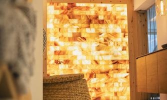 A modern designed room with a glowing salt stone wall. In the foreground, there is a basket and some decorative elements.