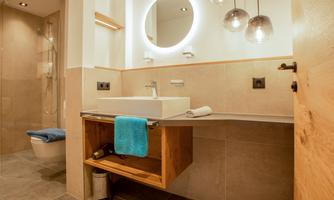 A modern bathroom with a sink and stylish lights. The walls are kept in neutral tones, and the space feels bright and inviting.