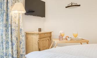 A cozy room with a television and a wooden table. On the table are two drinks and a small meal.