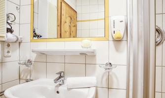 A modern bathroom with a sink and a mirror. The walls are tiled and the room feels bright and inviting.