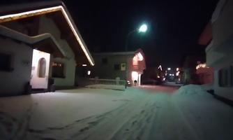 A snow-covered street at night with illuminated houses. The lights create a cozy atmosphere in the winter landscape.