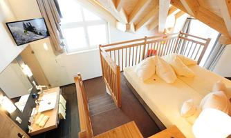A cozy bedroom with wooden details and a large window. It offers an inviting atmosphere with a double bed and modern amenities.