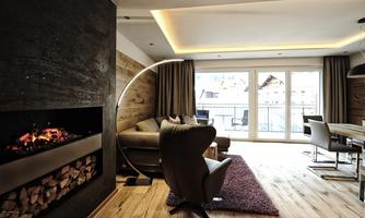 A modern living room with a cozy fireplace and large windows that let in plenty of daylight. The space is furnished with stylish furniture and a soft rug.