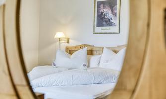 A cozy bedroom with a big bed and plush pillows. In the background, a framed picture hangs on the wall.