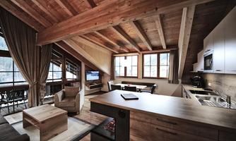 A modern attic apartment with wooden ceilings and large windows. The space is cozily furnished with a kitchen, a dining area, and a living area.