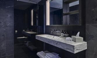 A modern bathroom with dark walls and an elegant marble vanity. In the background, the light reflects, creating a calming atmosphere.