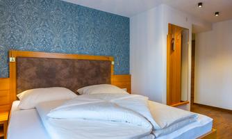 A modern bedroom with a double bed and an appealing wall design. The lighting creates a cozy atmosphere.